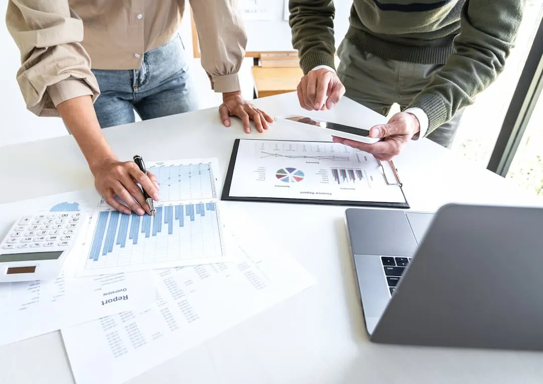 A budget being talked through over printed charts and a laptop